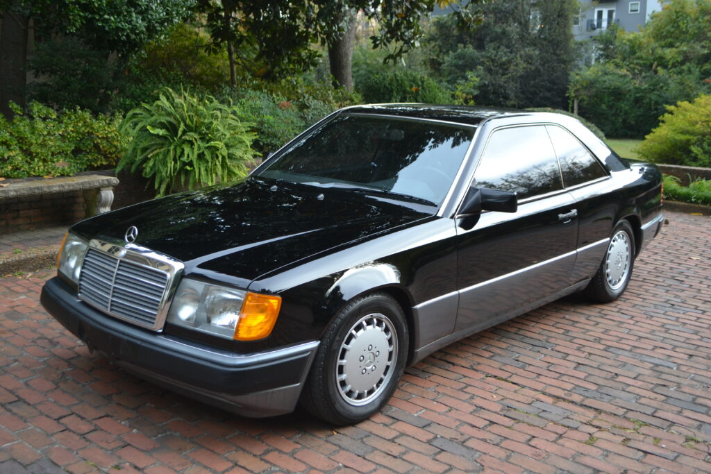 Mercedes-Benz W124 Coupe w kolorze czarnym na tle ogrodu