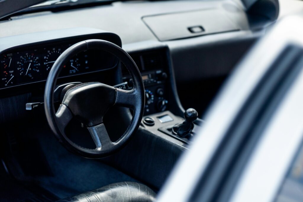 Wnętrze klasycznego samochodu z manualną skrzynią biegów i analogowymi zegarami