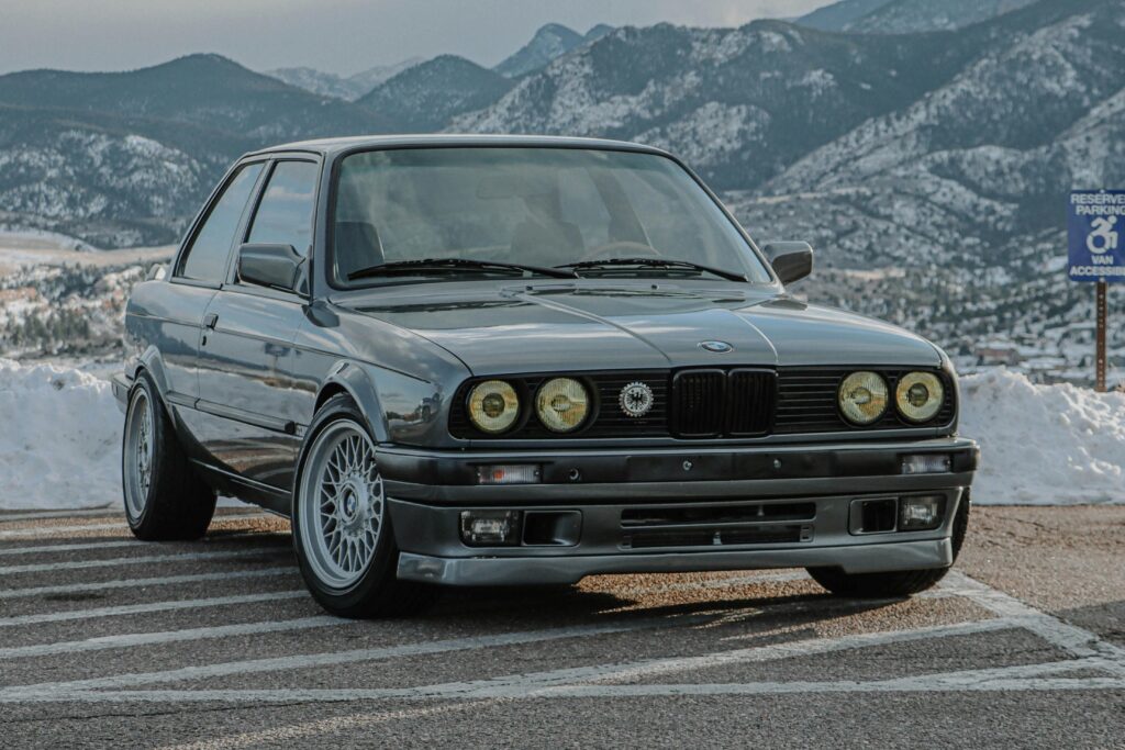 Klasyczne BMW serii 3 E30 zaparkowane na parkingu z górskim krajobrazem w tle