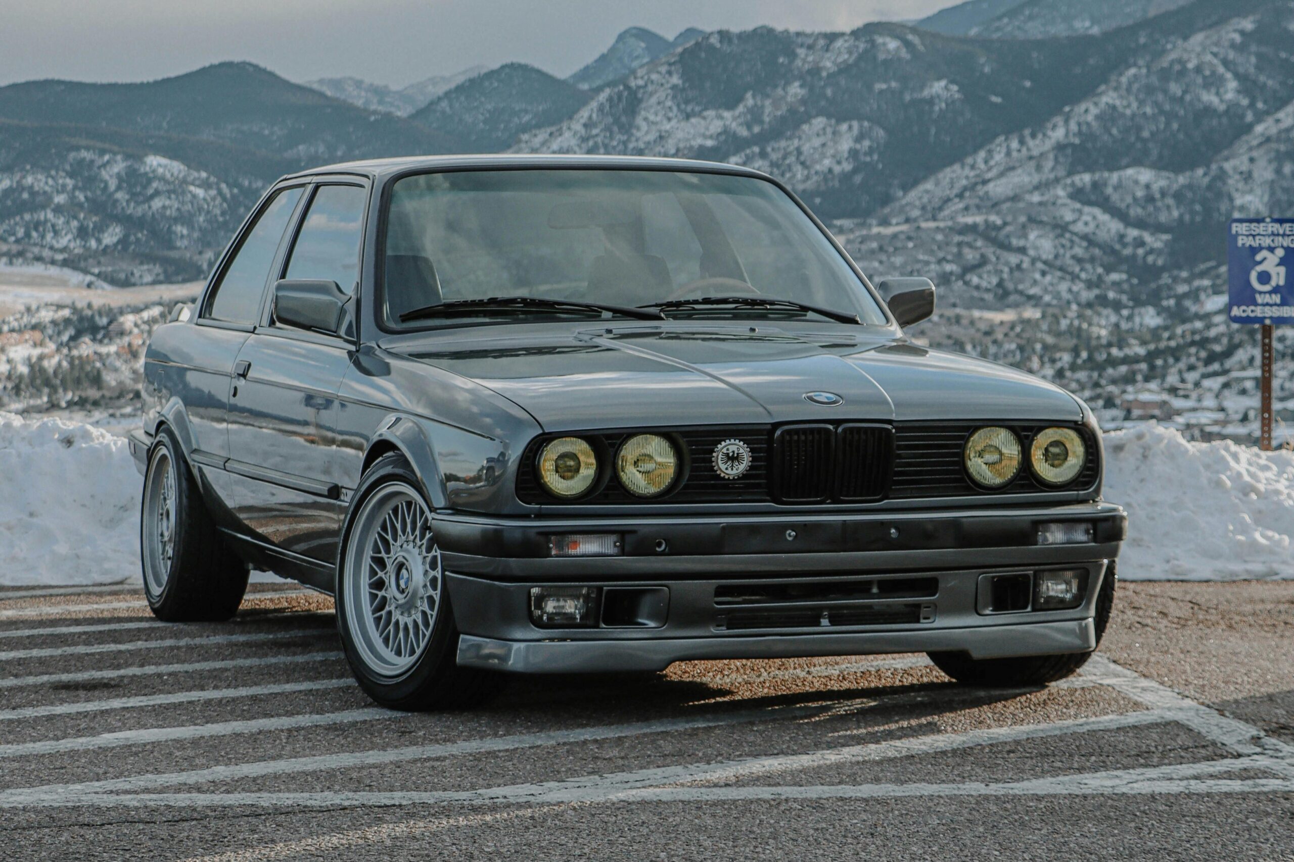 Klasyczne BMW serii 3 E30 zaparkowane na parkingu z górskim krajobrazem w tle